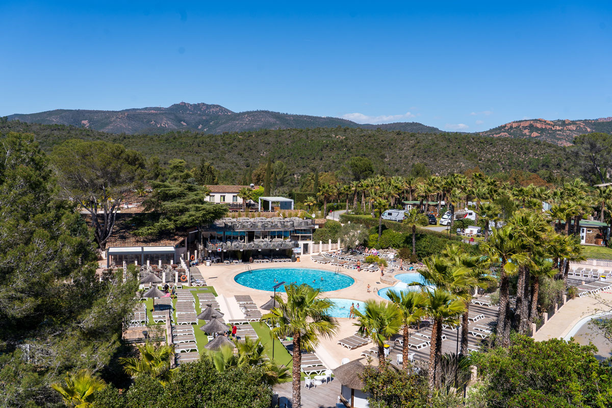 Vue aérienne de la piscine, des transats et du solarium d'Esterel Caravaning, face au massif de l'Estérel