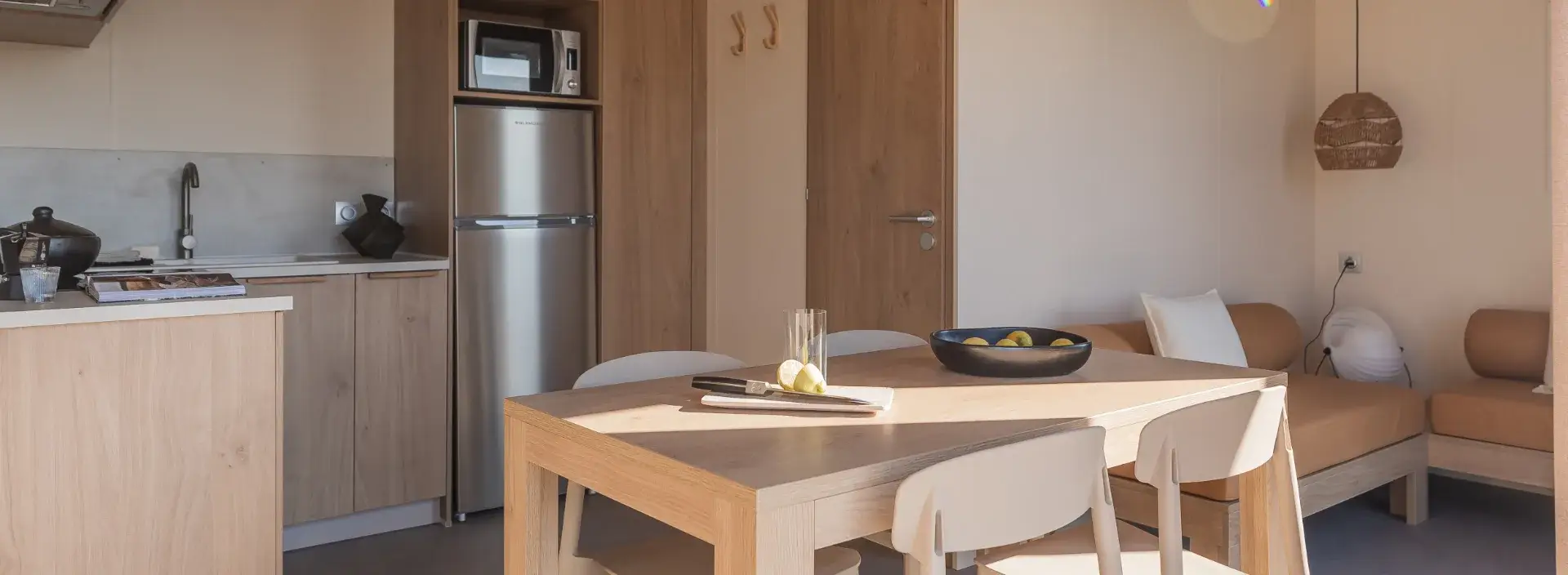 Espace repas du mobil-home Suite avec table en bois, cuisine et banquette