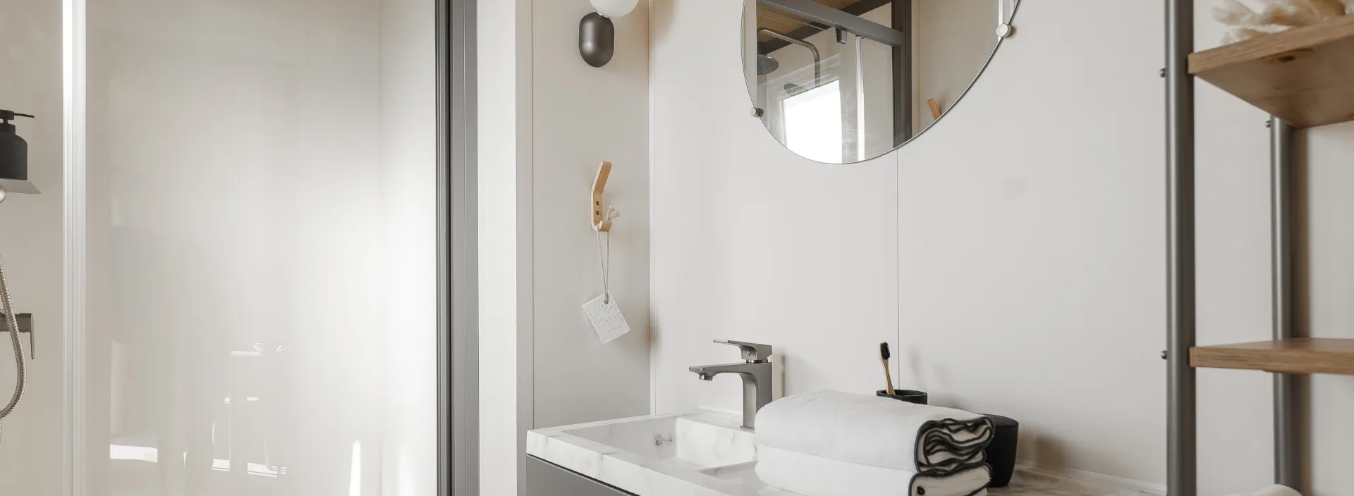 Salle d'eau du mobil-home Suite avec douche, vasque et miroir rond