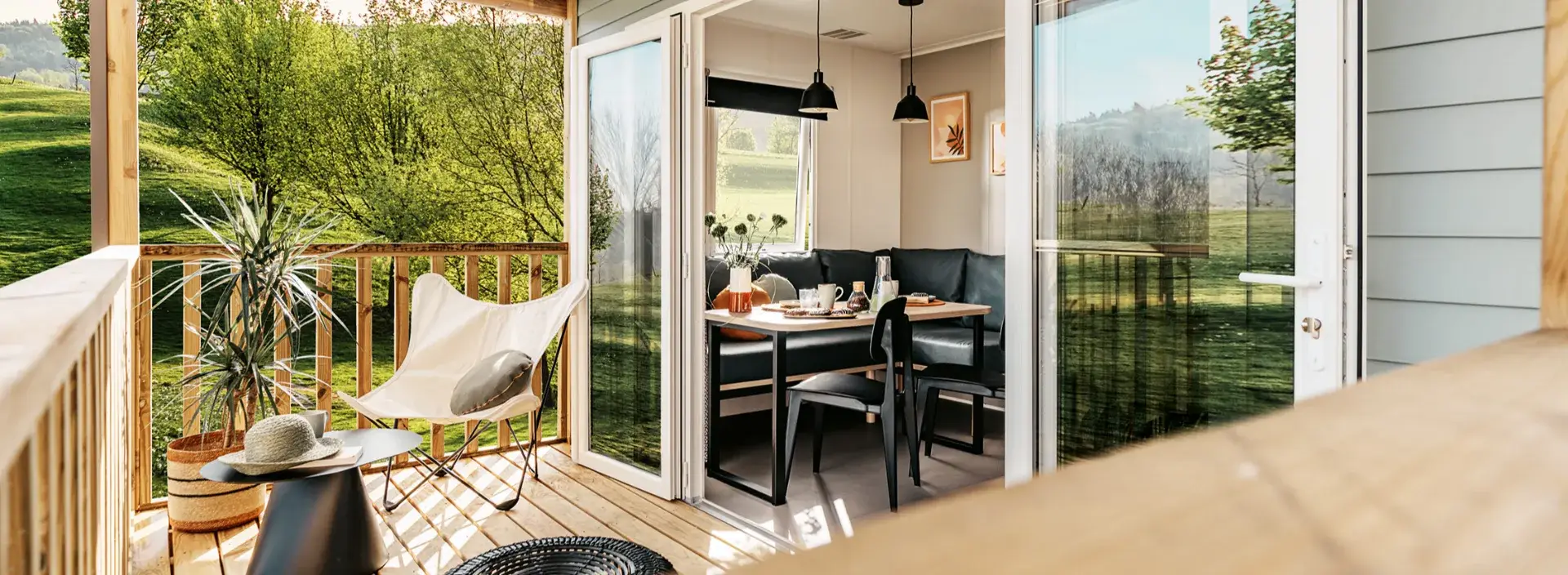 Terrasse couverte du mobil-home Villa avec salon de jardin et baie vitrée ouverte sur l'espace repas